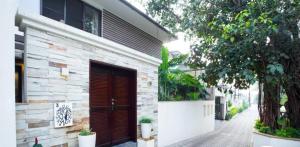 a brick building with a red door on a street at Frangipani Villa in Anjuna