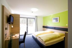 a bedroom with a bed and a desk and a television at Hotel und Kongresszentrum Wanderath in Baar