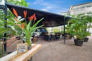 a patio with a black canopy with tables and plants at Golden Sands Beachfront Resort in Yorkeys Knob