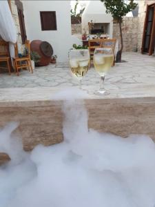 dos copas de vino blanco sentadas en un patio en House of Eleni, en Káthikas