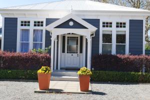 une maison bleue avec deux pots de fleurs devant elle dans l'établissement Havelock Cottage on St Georges, à Havelock North