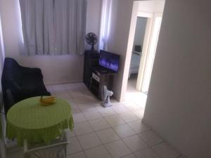 un salon avec une table et une télévision dans l'établissement Apt completo-Ar-TV-Portaria 24h-Piscina-Praia, à Campos dos Goytacazes