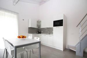 a white kitchen with a table and some chairs at La mansarda di Rossella in Pieve Di Ledro