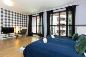 - une chambre avec un lit bleu et une télévision dans l'établissement Apartments Warsaw Bitwy Warszawskiej, à Varsovie