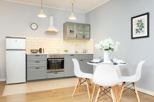 uma cozinha com electrodomésticos brancos e uma mesa com cadeiras brancas em Apartments Warsaw Bitwy Warszawskiej em Varsóvia