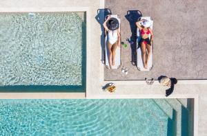 an overhead view of two women sitting in chairs next to a pool at Rodon Garden in Sarti
