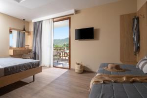 a bedroom with a bed and a television and a balcony at Rodon Garden in Sarti