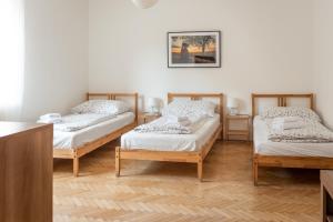 three beds in a room with white walls and wooden floors at Dobrý Kanec - Hostinec in Mělník