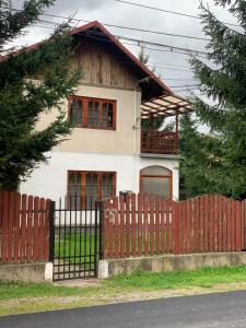 une maison avec une clôture rouge devant elle dans l'établissement Vila Busteni DORA, locatie superba strada Grivitei 36, à Buşteni