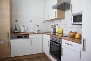 una cocina blanca con armarios blancos y fregadero en Central Premium Apartment FREE Parking & Self Check-in en Graz