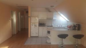 kuchnia z białymi szafkami, blatem i stołkami w obiekcie Bliss apartment w mieście Tata