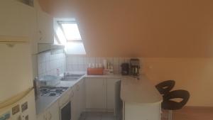 kuchnia z białymi szafkami, zlewem i oknem w obiekcie Bliss apartment w mieście Tata +6 zdjęć