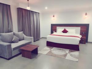 een slaapkamer met een bed, een stoel en een bank bij MY HOTEL Nizwa Residence Hotel Apartement نزوى ريزيدنس in Nizwa