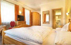 a bedroom with two beds and a flat screen tv at Zedernhof Gesundheits- & Wellnesshotel in Stamsried