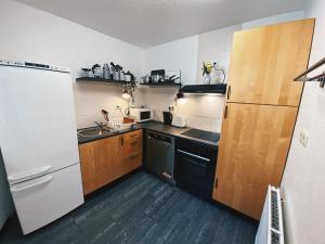 a kitchen with a white refrigerator and wooden cabinets at EcoLodge Bungalow in Oesterdeichstrich