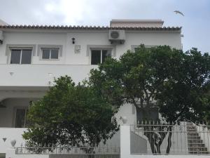 una casa blanca con árboles delante de ella en Villa Maria Alvor, en Alvor