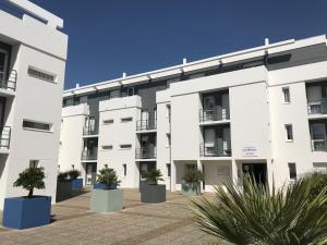 um edifício de apartamentos com vasos de plantas num pátio em Séjours & Affaires La Rochelle Les Minimes em La Rochelle