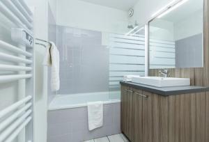 ein Badezimmer mit einem Waschbecken und einer Badewanne in der Unterkunft Résidence Odalys L'Ouillon in Saint-Sorlin-dʼArves