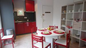 cocina con mesa blanca y armarios rojos en DOMAINE DU PLANAS - PATIO, en Ailhon