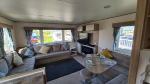 uma sala de estar com um sofá e uma mesa em Luxury 2019 8 berth Caravan with Hot Tub @ Tattershall Lakes em Tattershall