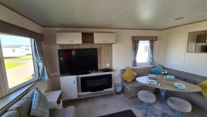 a living room with a couch and a table and a tv at Luxury 2019 8 berth Caravan with Hot Tub @ Tattershall Lakes in Tattershall