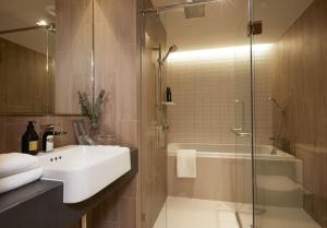 a bathroom with a sink and a shower and a tub at The Quarter Phromphong by UHG - SHA Extra Plus in Bangkok