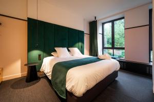 a bedroom with a large bed with a green headboard at Boutique Hôtel Vedette entre Namur et Dinant in Profondeville
