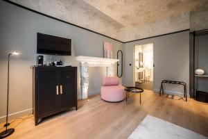 a living room with a tv and a chair at Hôtel Vedette in Profondeville