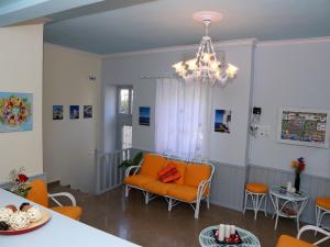 a living room with orange chairs and a chandelier at Theano Guesthouse in Hydra