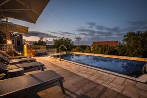 a swimming pool with chairs and an umbrella at Faros Residence Adults Only in Fiskardho