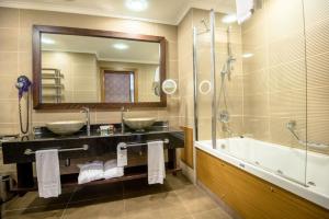 a bathroom with two sinks and a tub and a mirror at Korineum Golf & Beach Resort in Kyrenia