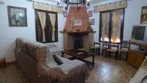 uma sala de estar com um sofá e uma lareira em Casa Rural Al-Mofrag y Apartamentos El Mirador de Monfragüe em Villarreal de San Carlos