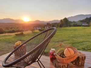 a chair with a basket of fruit on a table with the sunset at Căsuța Top House in Zărneşti