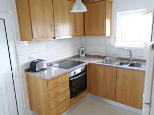 a small kitchen with wooden cabinets and a sink at Casa da Ti Emília in Cardigos