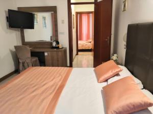 a bedroom with a bed and a desk and a television at Hotel Europa in Modena