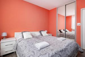 um quarto com paredes cor-de-laranja, uma cama e um espelho. em Apartments Dworcowa by Renters em Kolobrzeg