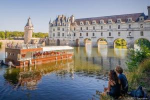 two people sitting on the bank of a river with a boat at Recent house in a hamlet near the Cher in Athée-sur-Cher