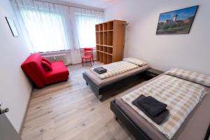 a bedroom with two beds and a red chair at Stadthaus Seeblick G5 - Hostel in Friedrichshafen
