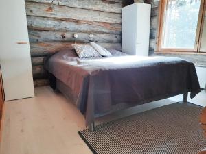 1 dormitorio con 1 cama con pared de madera en Riemula cabin, en Kuusamo