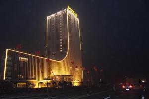 un edificio alto con luces encendidas por la noche en Yangzhong Firth Jinling Grand Hotel, en Yangzhong