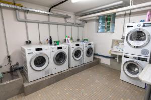a laundry room with three washing machines and a sink at Stadthaus Seeblick G5 - Hostel in Friedrichshafen