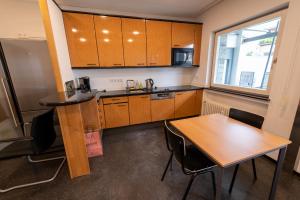 una cucina con armadi in legno, tavolo e finestra di Stadthaus Seeblick G5 - Hostel a Friedrichshafen