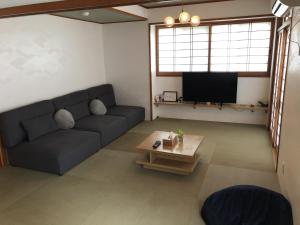 a living room with a couch and a tv at Santiago Guesthouse Naha in Naha