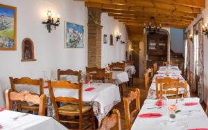 uma sala de jantar com mesas brancas e cadeiras de madeira em Posada La Plaza em Canillas de Albaida