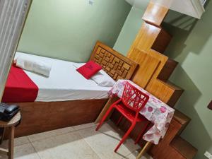 a small bedroom with a bed and a red chair at RedDoorz near Colgante Bridge Naga City in Naga