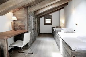 a bedroom with two beds and a desk and a table at Chalet Skyfall by Mrs Miggins in Grimentz