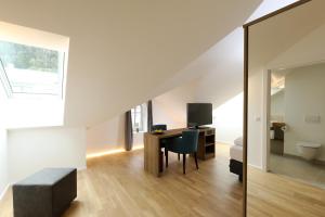 an attic room with a desk and a bedroom at Das Jedermann Boutiquehotel mit Stadtgarten in Salzburg