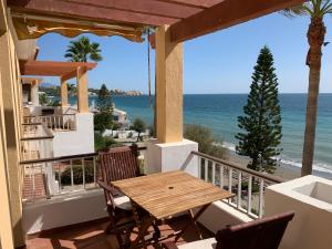 een tafel en stoelen op een balkon met uitzicht op de oceaan bij Apartamento luminoso 1ª línea Arena Beach_Estepona in Estepona