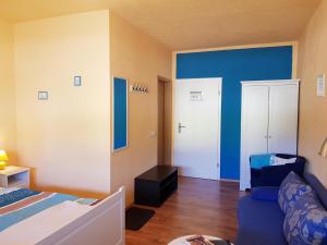 a bedroom with blue walls and a bed and a couch at Pension An der Erzgebirgsbahn in Kurort Oberwiesenthal