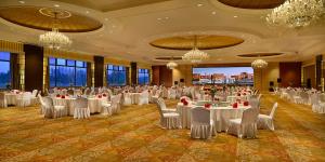 un salón de banquetes con mesas y sillas blancas y lámparas de araña en Crowne Plaza Ordos, an IHG Hotel, en Ordos